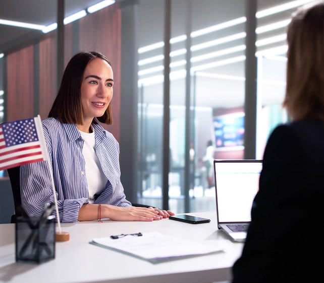 Woman receiving guidance during an immigration consultation, with an American flag on the desk.