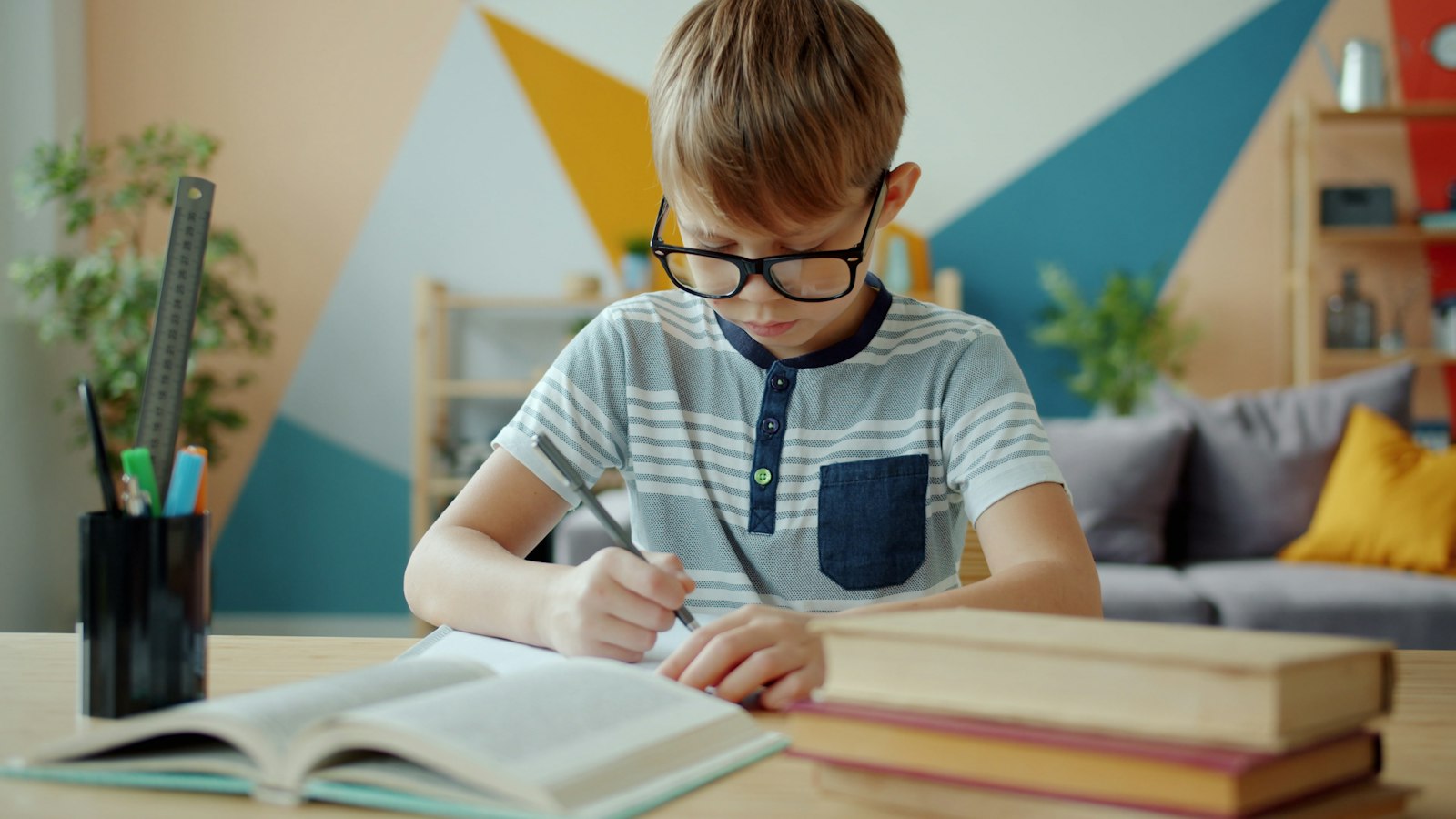 Boy with glasses concentrating on homework at a desk